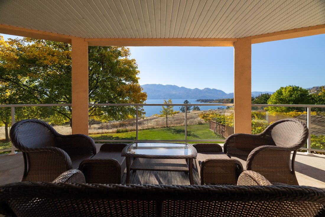 The covered deck with seating, looking over the grounds toward the lake