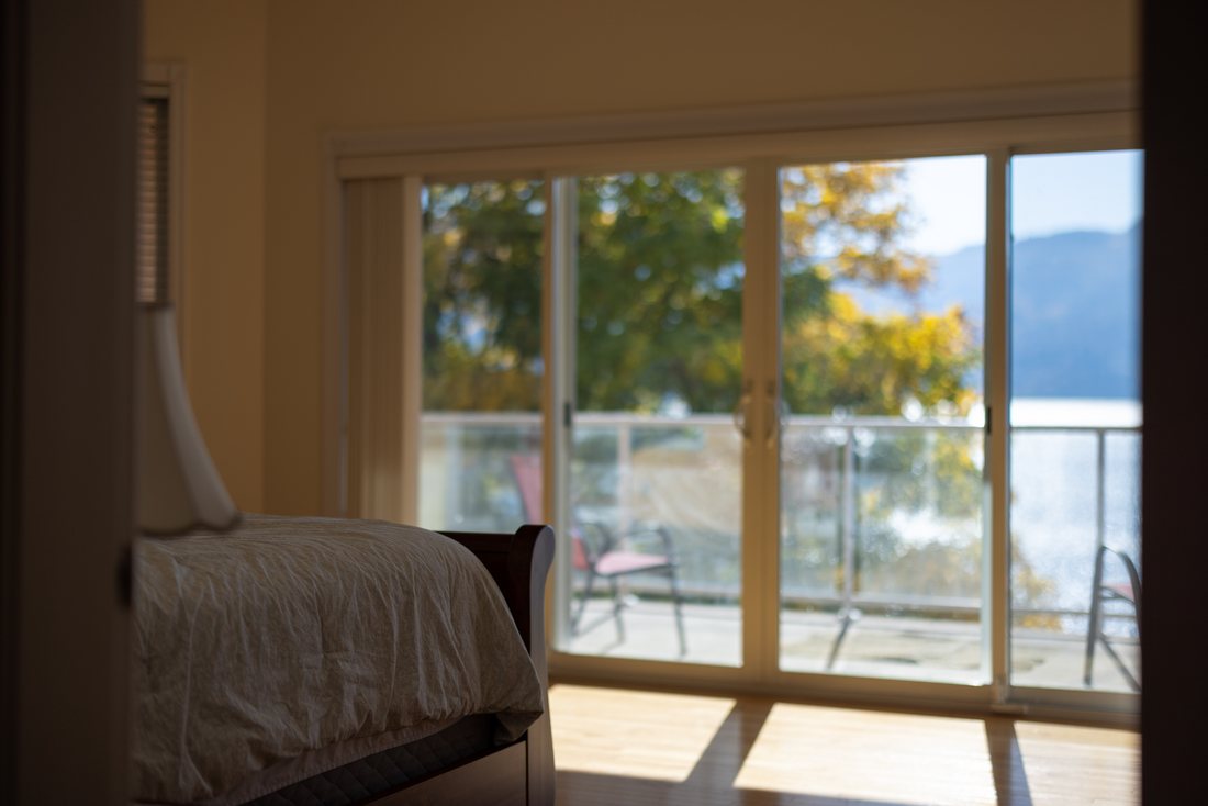 View from the master bedroom — sliding doors to a balcony, Okanagan Lake beyond